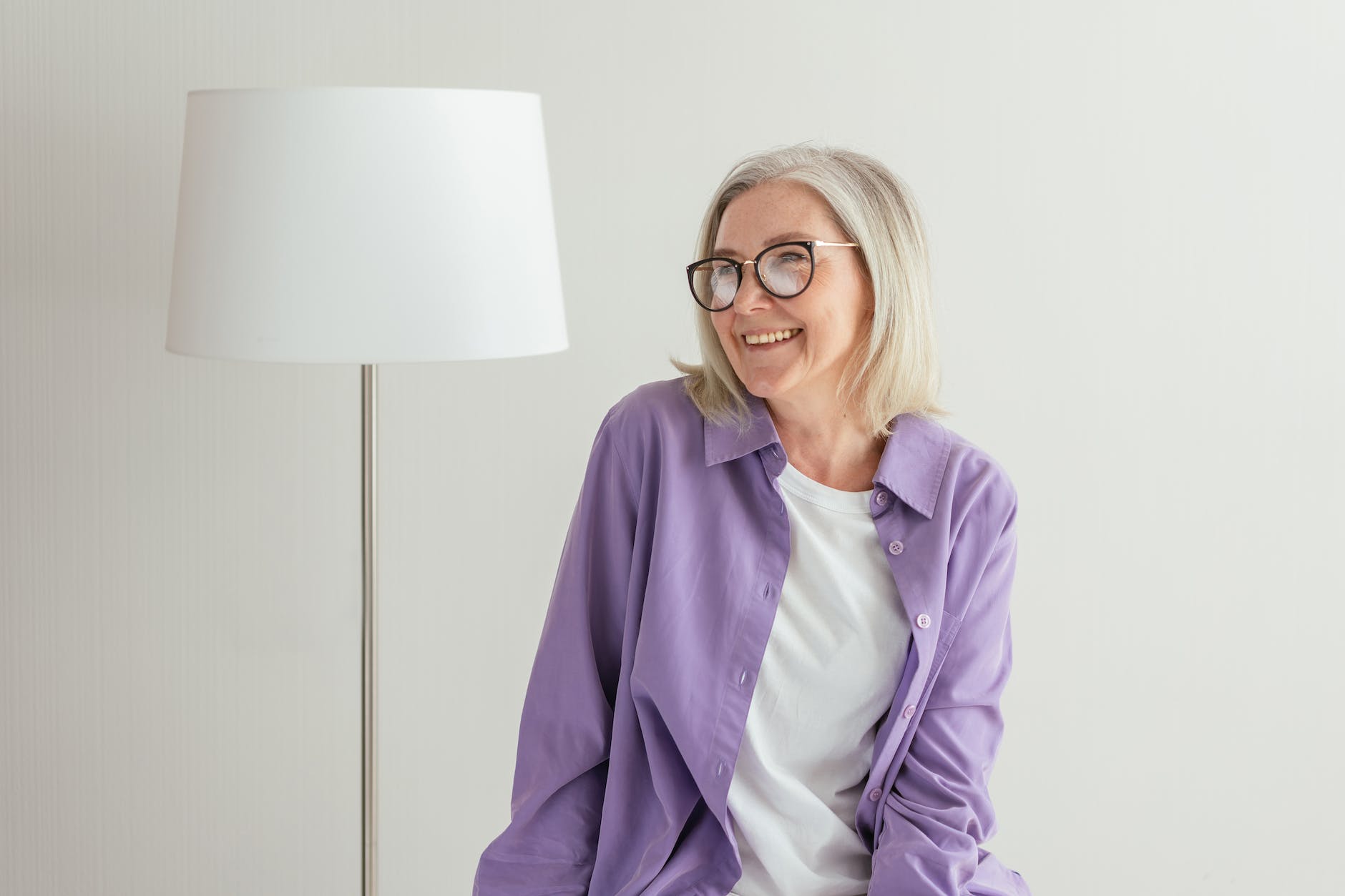 a Canadian senior in purple long sleeves smiling while wearing eyeglasses looking at OAS info